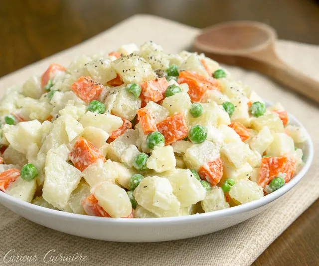 Ensalada Rusa is the Spanish name for a side dish that is popular in many countries but is best known as Oliver Salad, or Russian Potato Salad. This well known potato salad is full of vegetables, like peas, carrots, onions, and more. | www.CuriousCuisiniere.com 