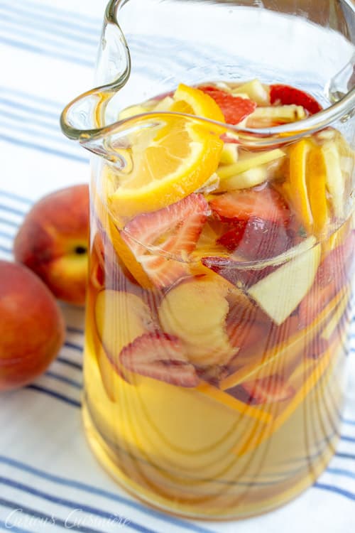 This Strawberry Peach Sangria is a fun twist on Spanish White Sangria. Fresh fruit, a crisp white wine, and a splash of brandy make this a summer favorite! | www.CuriousCuisiniere.com