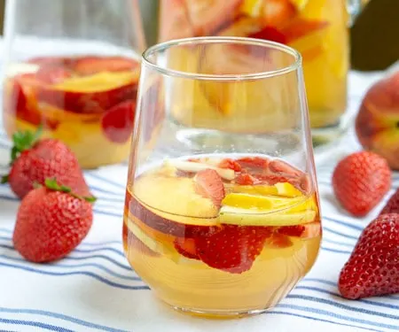 This Strawberry Peach Sangria is a fun twist on Spanish White Sangria. Fresh fruit, a crisp white wine, and a splash of brandy make this a summer favorite! | www.CuriousCuisiniere.com