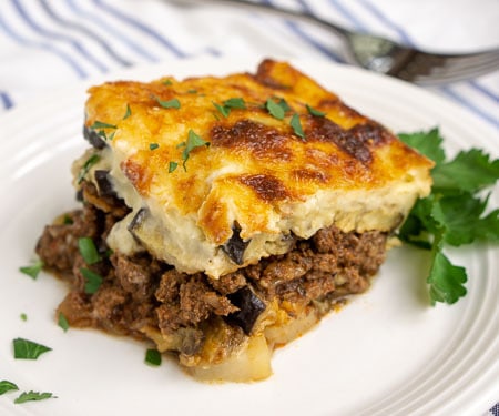 Greek Moussaka is an eggplant casserole filled with layers of eggplant and a warmly spiced meat sauce, all covered in a rich béchamel sauce. This is a recipe for some serious Greek comfort food! | www.CuriousCuisiniere.com