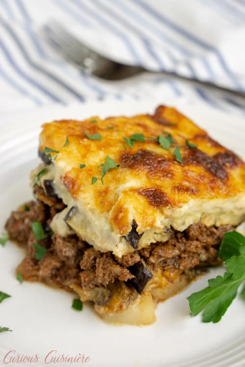 Greek Moussaka is an eggplant casserole filled with layers of eggplant and a warmly spiced meat sauce, all covered in a rich béchamel sauce. This is a recipe for some serious Greek comfort food! | www.CuriousCuisiniere.com 