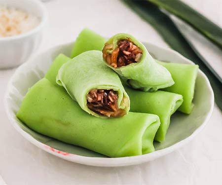 Kueh dadar is a Southeast Asian snack with a vibrant color. Image with crepe opened to see filling. | www.CuriousCuisiniere.com