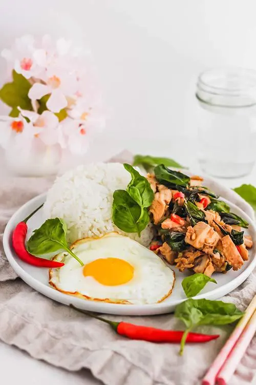 Pad Krapow Gai, Thai Basil Chicken, with pink chopsticks and flowers. | www.CuriousCuisiniere.com