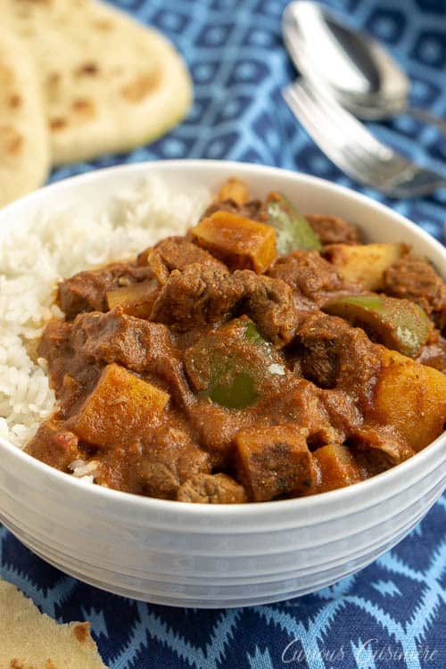 This Madras Curry is a warming dish that is perfect for a cool evening. This slow cooker beef curry brings deep, comforting flavors and tender meat with little effort. | www.CuriousCuisiniere.com