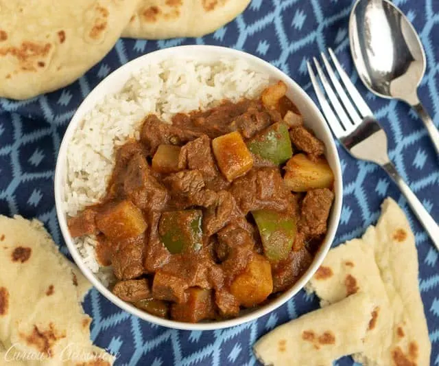 Overhead image of Beef Madras Curry with Vegetables and rice and naan flatbread. | www.CuriousCuisiniere.com