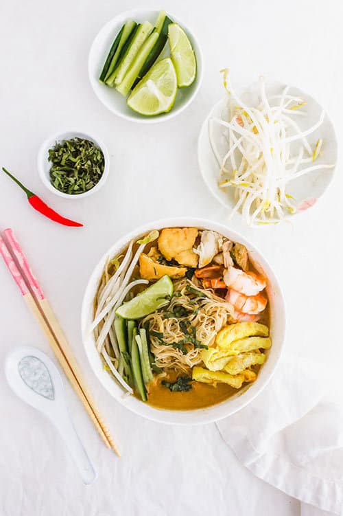 Sarawak laska bowl with garnishes of bean sporuts and cucumbers | www.CuriousCuisiniere.com