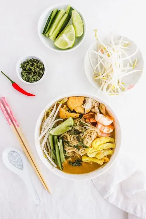 Sarawak laska bowl with garnishes of bean sporuts and cucumbers | www.CuriousCuisiniere.com