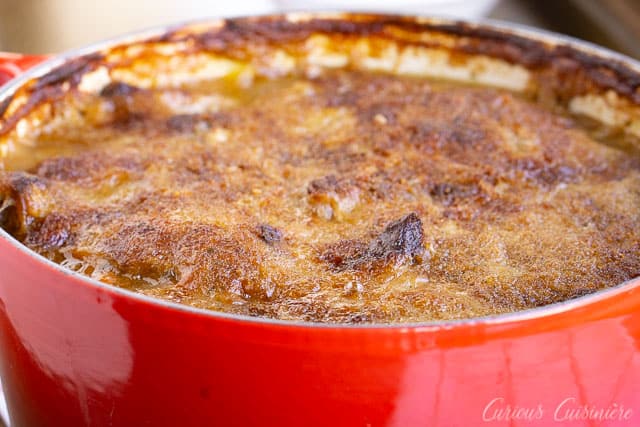 A golden crusted top of cassoulet in a red Dutch oven. | www.CuriousCuisiniere.com