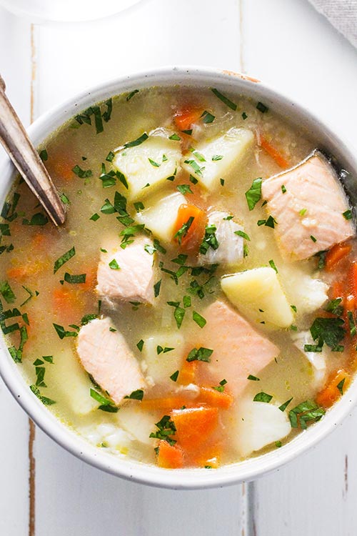 Draufsicht auf eine Schüssel Ukha, russische Fischsuppe. Fisch wird sanft mit Kartoffeln und Karotten in einer reichen Brühe mit Lorbeer und schwarzem Pfeffer gewürzt gekocht. | www.CuriousCuisiniere.com 