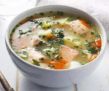 A bowl of Ukha, Russian fish soup. Fish is gently cooked with potatoes and carrots in a rich broth seasoned with bay and black pepper. | www.CuriousCuisiniere.com