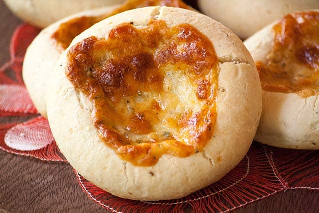 Horizontal close up of Chipa 4 quesos, Paraguayan cassava and cheese bread with golden cheese baked on top. 