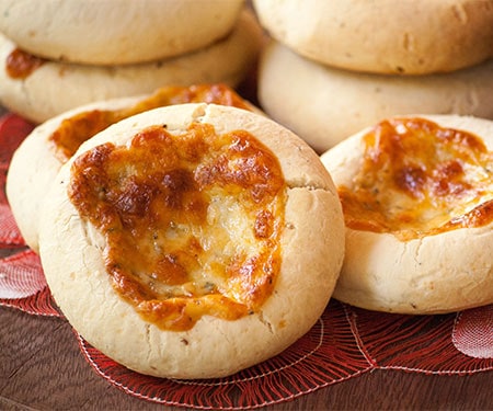 Small image of horizontal close up of Chipa 4 quesos, Paraguayan cassava and cheese bread with golden cheese baked on top.