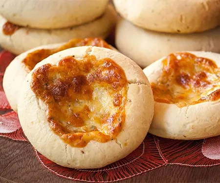 Small image of horizontal close up of Chipa 4 quesos, Paraguayan cassava and cheese bread with golden cheese baked on top.