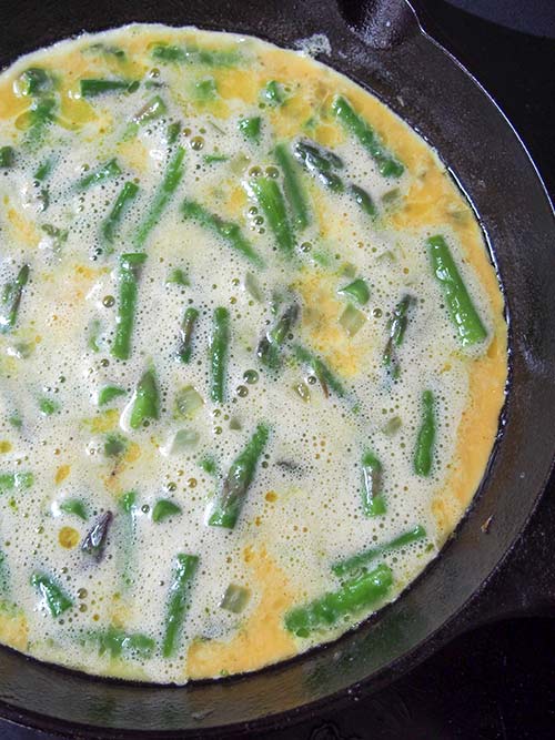 Ingredients for an asparagus fritatta in a cast iron pan.