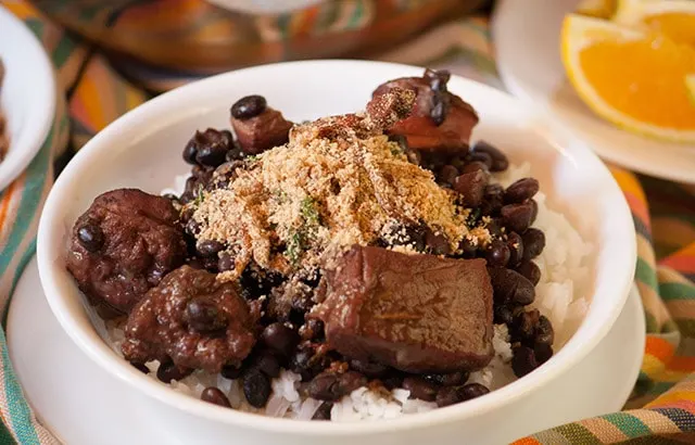 Feijoada, Brazilian black bean and pork stew with farofa, toasted cassava flour in a bowl over rice