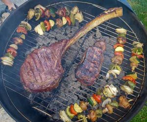 Tomahawk steak and veggie kebabs on the grill.
