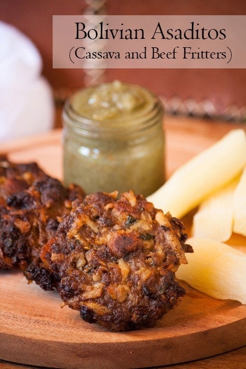 Asaditos (Bolivian Cassava and Beef Fritters) with boiled cassava and spicy sauce on a wooden board
