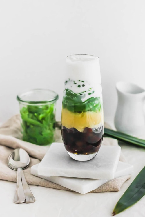Cendol, Malaysian pandan jellies, layered with red azuki beans, yellow mung beans, and coconut milk in a glass. Featuring green pandan jellies. 