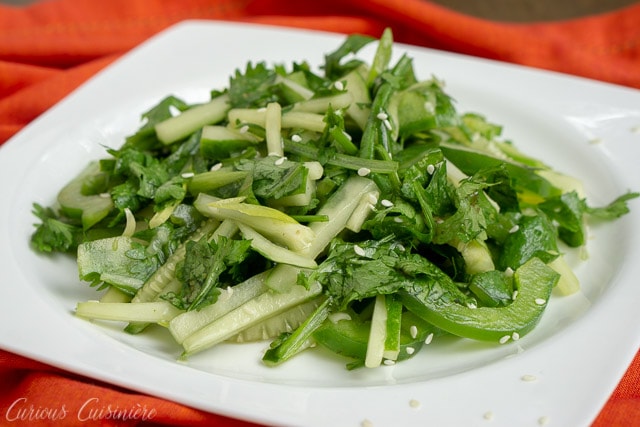 Chinese Tiger Salad - Lao Hu Cai - with cucumbers, cilantro, green peppers in a sesame oil dressing. on a white plate with a red background. 