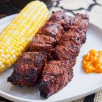 Anticuchos, Peruvian grilled beef skewers on a plate with corn