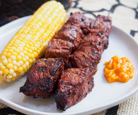 Anticuchos, Peruvian grilled beef skewers on a plate with corn