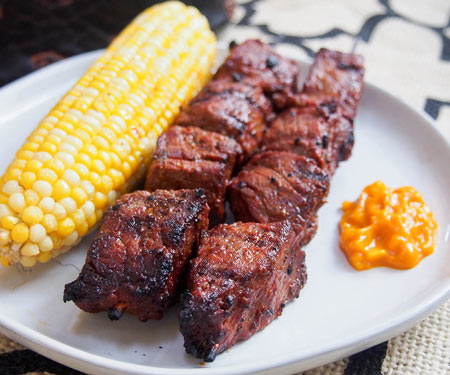 Anticuchos, Peruaanse gegrild rundvlees spiesjes op een bord met maïs