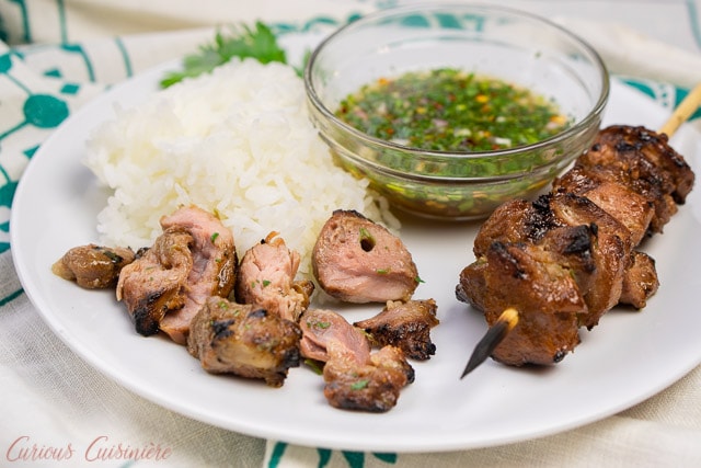 Thai pork kabobs with rice and dipping sauce with pieces taken from the skewer