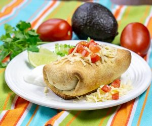 Baked chicken chimichanga topped with cheese and diced tomato, small image