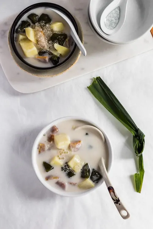 Bubur Cha Cha, a creamy and sweet Malaysian dessert made from yam, taro, and coconut milk. With a pandan leaf. 