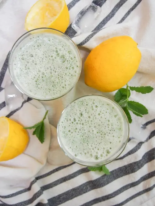 Overhead image of two frothy glasses of Limonana Middle Eastern Mint Lemonade.