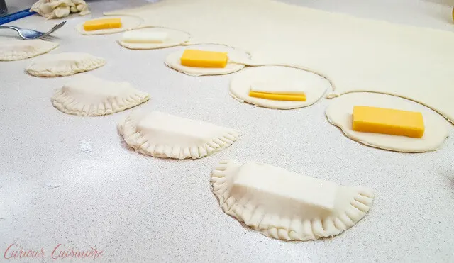 Filling and sealing Brazilian Pastel de Queijo, cheese pastries