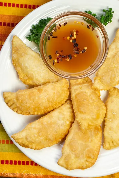 Brazilian Pastel de Queijo (Cheese Pastries) on a plate with hot sauce, overhead vertical image