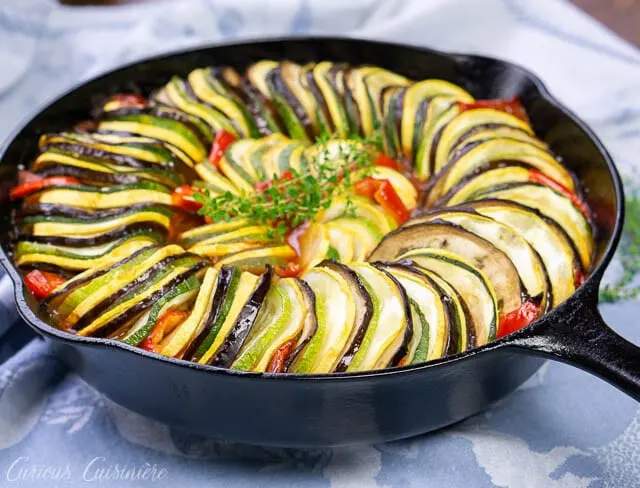 Whole pan shot of baked layered ratatouillewith eggplant, summer squash, zucchini, tomatoes, and red peppers.