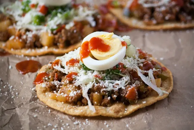 Honduran enchiladas with beef, hard boiled egg, and tomato sauce up close