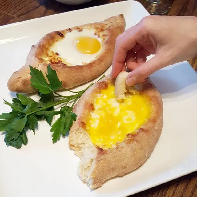 Dipping bread into Georgian cheese and egg bread