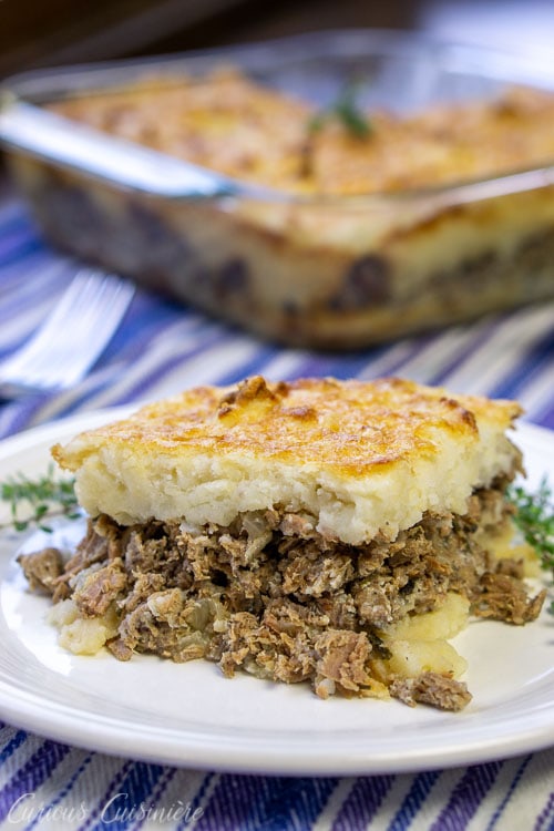 Slice of French Hachis Parmentier Potato and Beef Casserole with whole dish behind