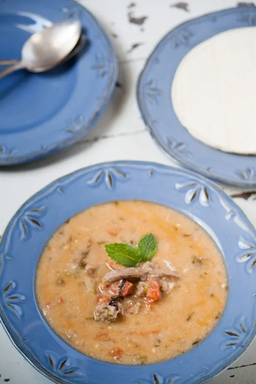 A blue bowl of Indio Viejo (Nicaraguan Beef Stew) with tortillas