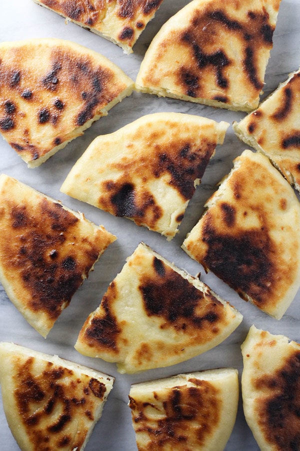 Imeruli Khachapuri - Georgian cheese filled bread cut into quarters and scattered across a marble board