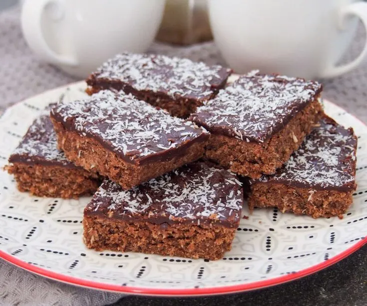 Stacked chocolate slice topped with flaked coconut
