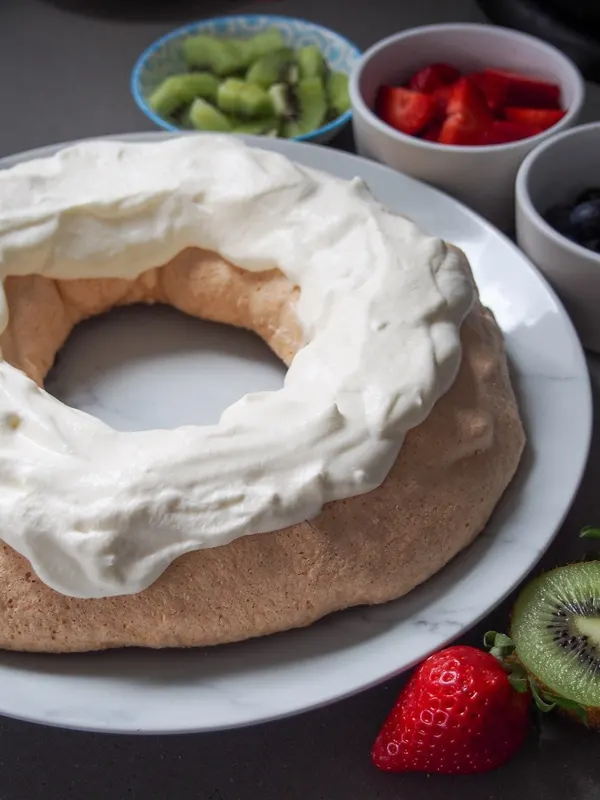 Australian Christmas Pavlova wreath topped with cream before adding fruit