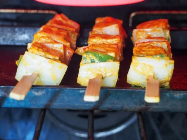 Cooking Paneer Tikka under a broiler