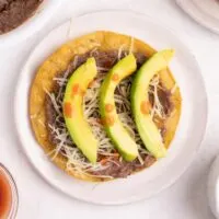 Catrachas Honduran bean tostada with avocado and hot sauce - horizontal