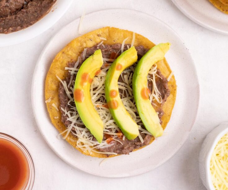 Catrachas Honduran bean tostada with avocado and hot sauce - horizontal