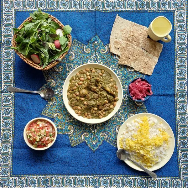 Persian ghormeh sabzi - herb stew served with lavash, shirazi salad, onions, rice, and a green salad
