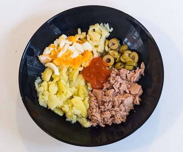 Ingredients for a Tunisian street food sandwich - tuna with olives, eggs, potatoes, and harissa